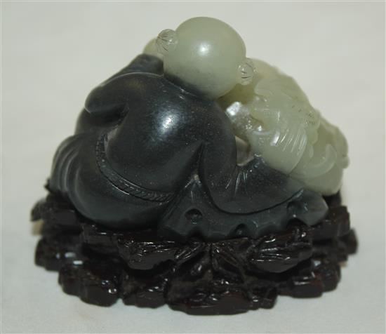 A Chinese pale celadon and dark grey jade and stand